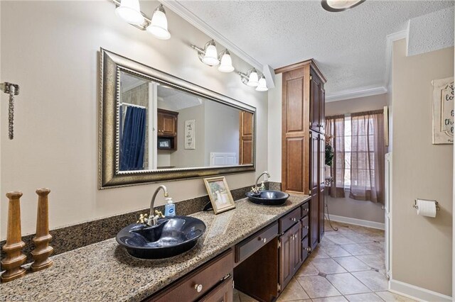 full bath with a textured ceiling, ornamental molding, a sink, and tile patterned flooring