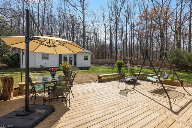 wooden deck featuring french doors, outdoor dining area, a fenced backyard, an outdoor fire pit, and a yard