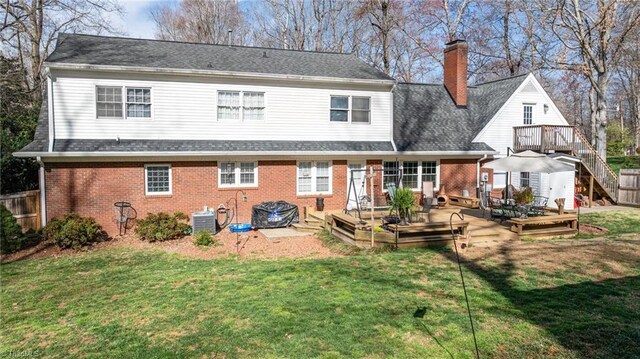 rear view of house with brick siding, a yard, and a deck