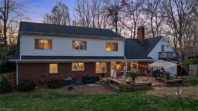 back of house featuring a chimney, a lawn, a wooden deck, fence private yard, and a gazebo