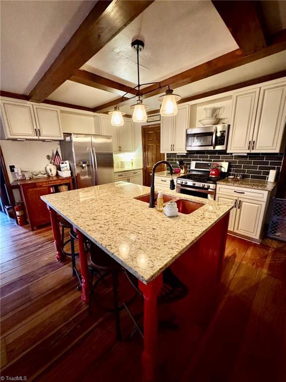 kitchen with stainless steel appliances, dark wood-type flooring, a sink, white cabinetry, and tasteful backsplash