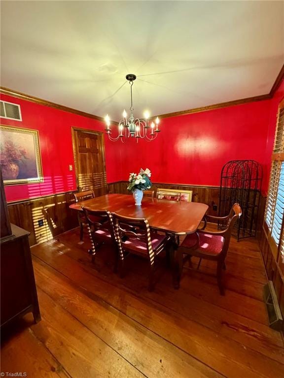 dining space with hardwood / wood-style floors, wainscoting, visible vents, and an inviting chandelier