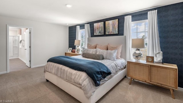 carpeted bedroom featuring multiple windows and connected bathroom