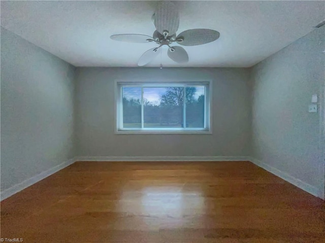 empty room with a ceiling fan, baseboards, and wood finished floors