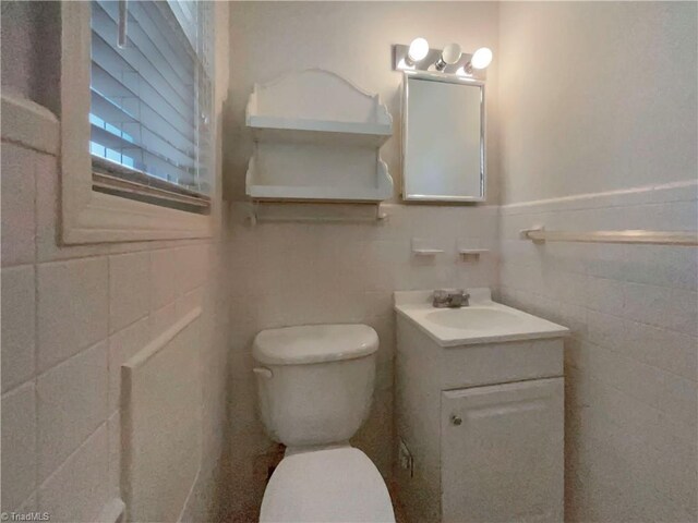 bathroom featuring tile walls, a wainscoted wall, vanity, and toilet