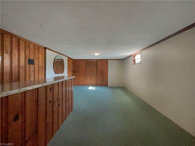 carpeted empty room featuring ornamental molding and wood walls