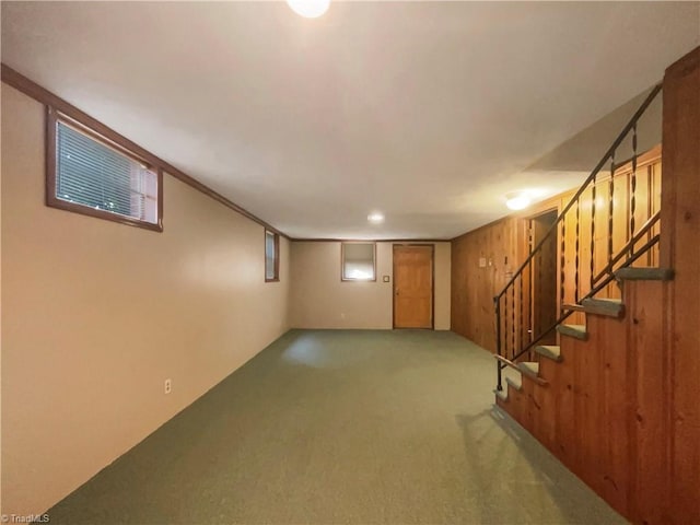 basement with carpet floors, wood walls, and stairs