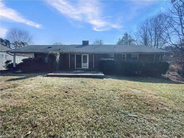 back of property with a carport, a patio area, and a lawn