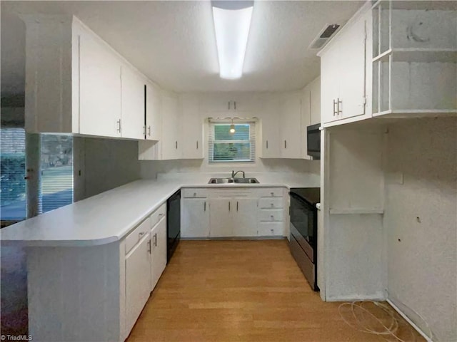 kitchen featuring light countertops, white cabinetry, a sink, and electric range
