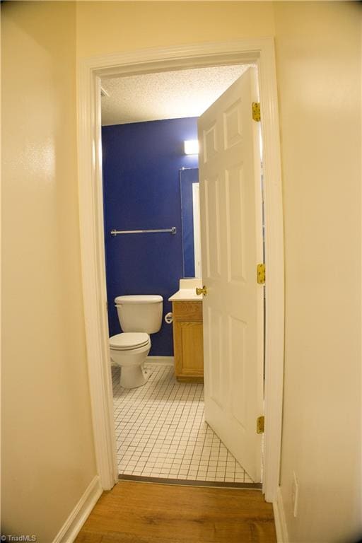 bathroom with toilet, vanity, a textured ceiling, and hardwood / wood-style flooring