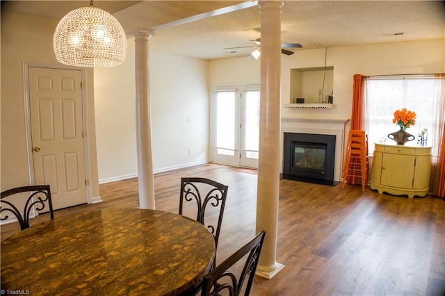 dining room with decorative columns, plenty of natural light, hardwood / wood-style floors, and ceiling fan with notable chandelier