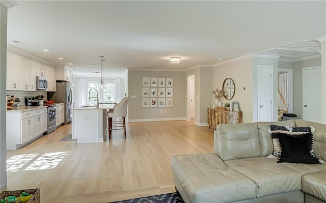 living area featuring baseboards, ornamental molding, light wood-style flooring, and recessed lighting
