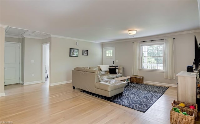 living room with crown molding, light wood-style flooring, attic access, and baseboards
