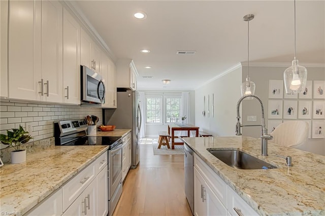kitchen with a sink, stainless steel appliances, ornamental molding, visible vents, and white cabinets