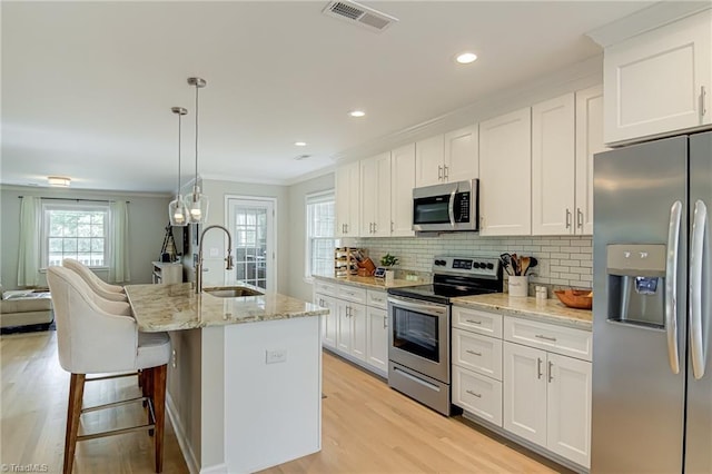 kitchen featuring a sink, stainless steel appliances, ornamental molding, visible vents, and decorative backsplash