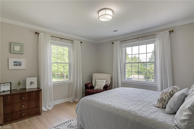 bedroom featuring crown molding, light wood-type flooring, visible vents, and baseboards
