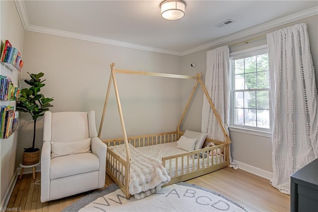 bedroom with crown molding, baseboards, visible vents, and wood finished floors
