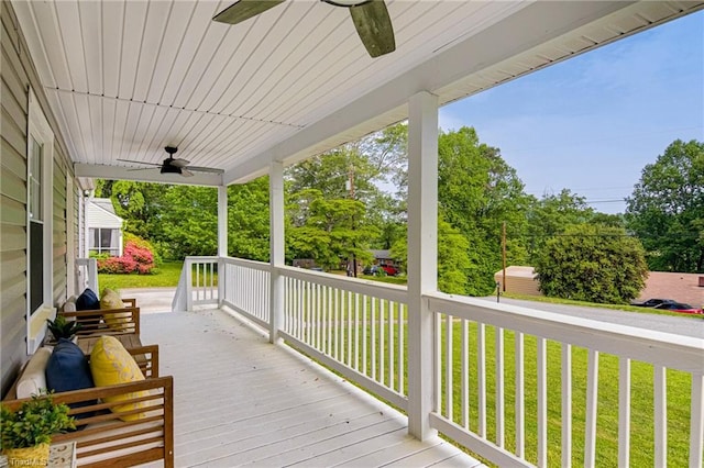 wooden deck featuring a porch, ceiling fan, and a lawn