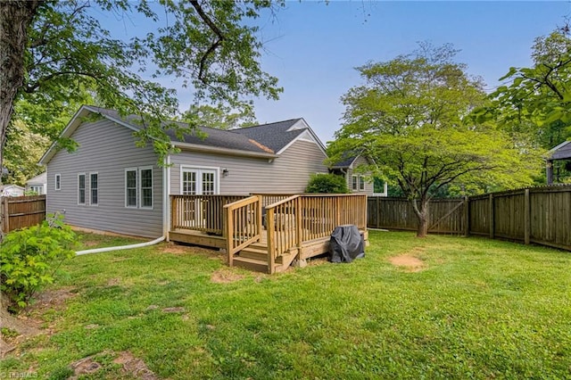 back of property with a fenced backyard, a deck, and a lawn