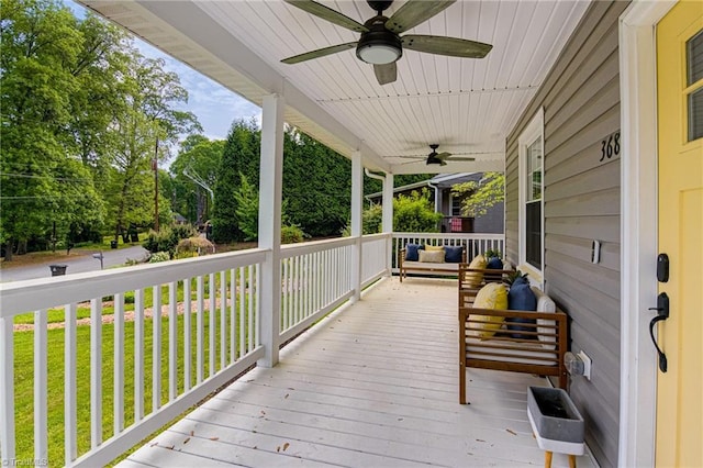 wooden deck with a ceiling fan, a yard, an outdoor living space, and covered porch