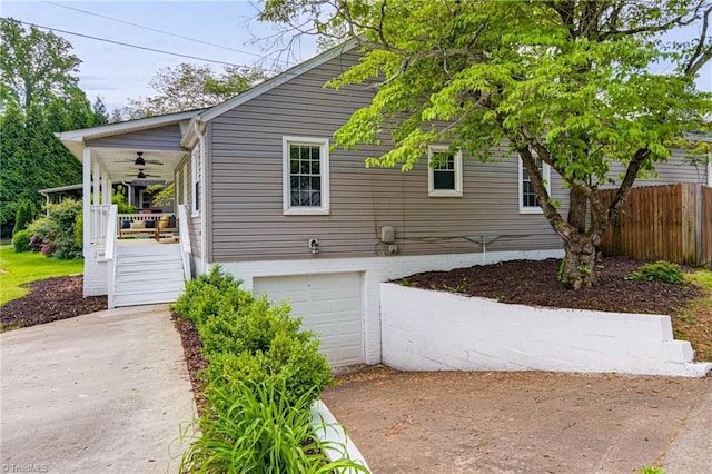 view of side of home with concrete driveway, covered porch, a garage, and fence