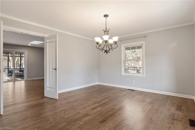 spare room with a wealth of natural light, ornamental molding, dark hardwood / wood-style floors, and a chandelier