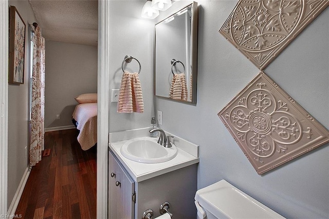 bathroom with vanity, a textured ceiling, hardwood / wood-style floors, and toilet