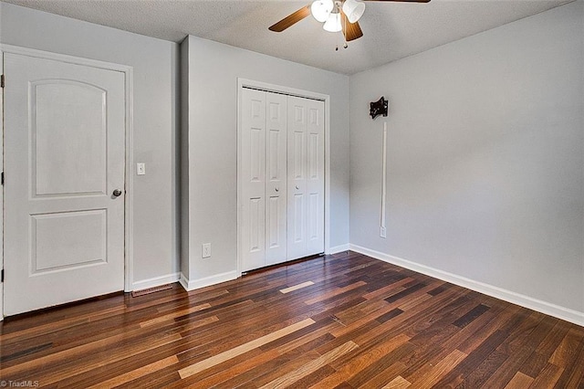 unfurnished bedroom featuring a textured ceiling, dark wood-type flooring, ceiling fan, and a closet