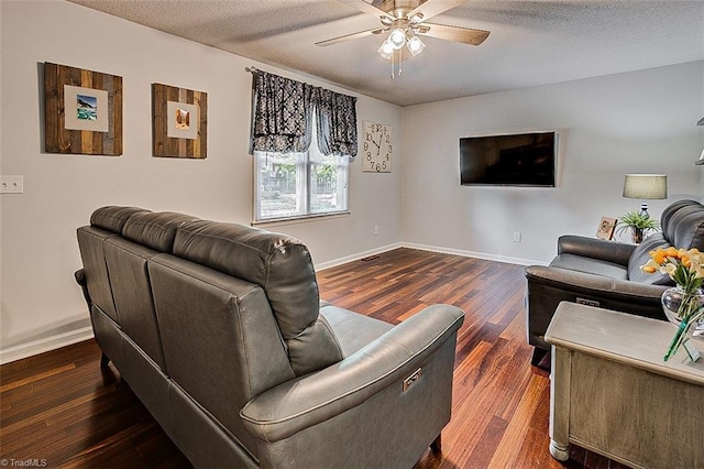 living room with a textured ceiling, dark hardwood / wood-style flooring, and ceiling fan