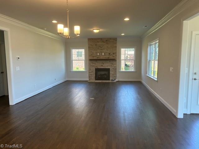 unfurnished living room with plenty of natural light, dark hardwood / wood-style floors, and a stone fireplace