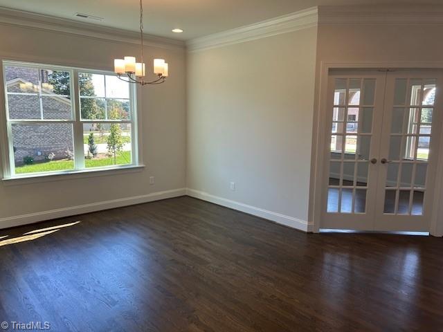 spare room with french doors, dark hardwood / wood-style floors, crown molding, and a chandelier