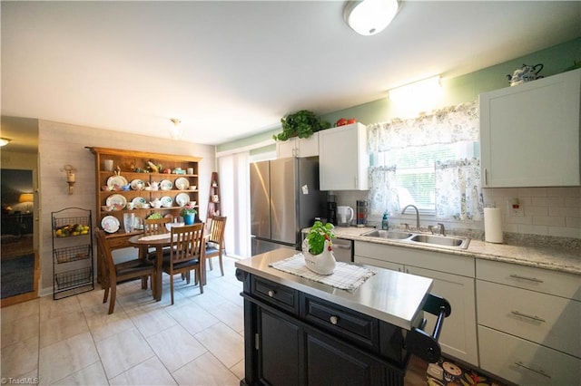 kitchen featuring white cabinets, stainless steel fridge, decorative backsplash, and sink