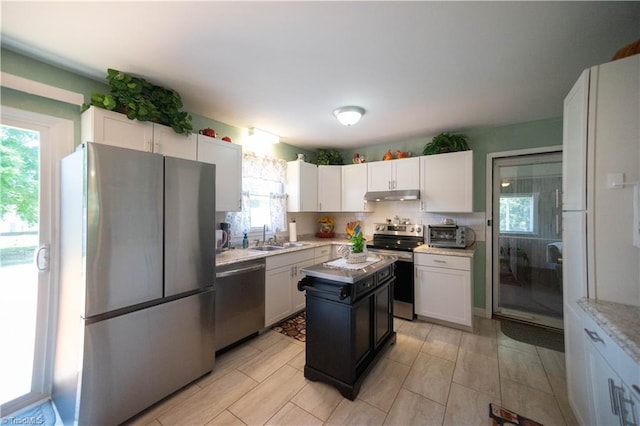 kitchen with white cabinetry, a center island, sink, stainless steel appliances, and tasteful backsplash