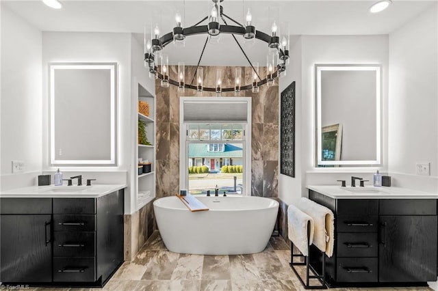 bathroom with a tub, vanity, and an inviting chandelier