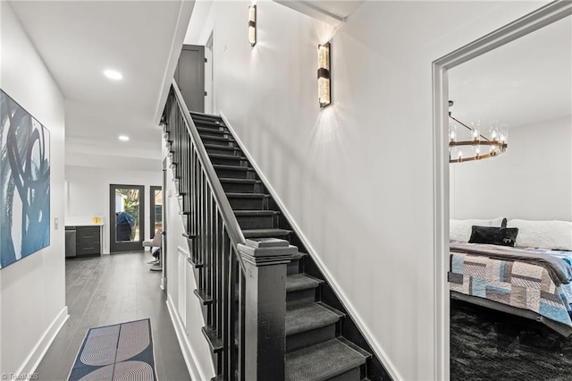 stairs with wood-type flooring and a notable chandelier