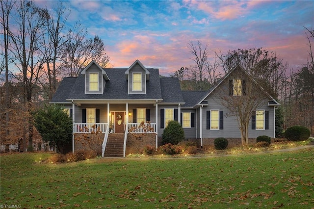 cape cod-style house with covered porch and a yard