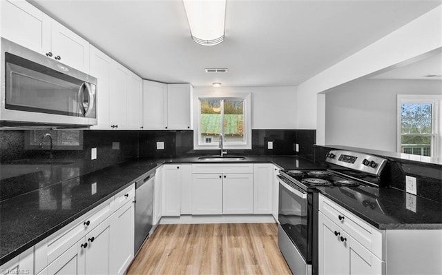 kitchen featuring white cabinetry, sink, backsplash, dark stone countertops, and appliances with stainless steel finishes