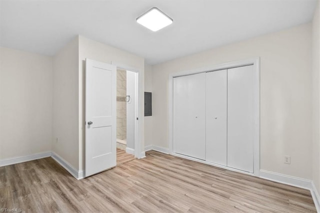 unfurnished bedroom featuring electric panel, a closet, and light hardwood / wood-style floors