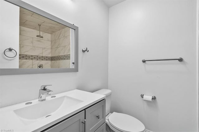 bathroom with vanity, toilet, and tiled shower