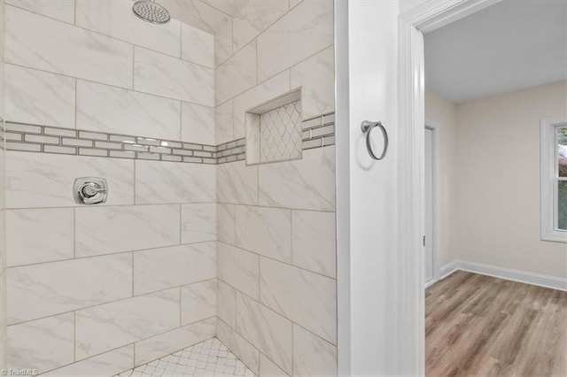 bathroom featuring a tile shower and wood-type flooring