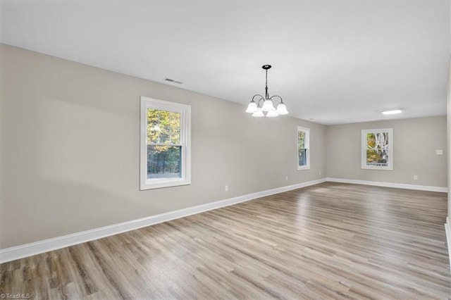 unfurnished room featuring light hardwood / wood-style flooring and a chandelier