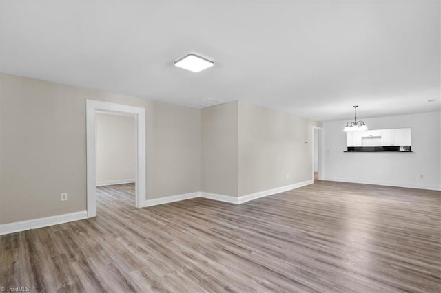 spare room with an inviting chandelier and light hardwood / wood-style flooring