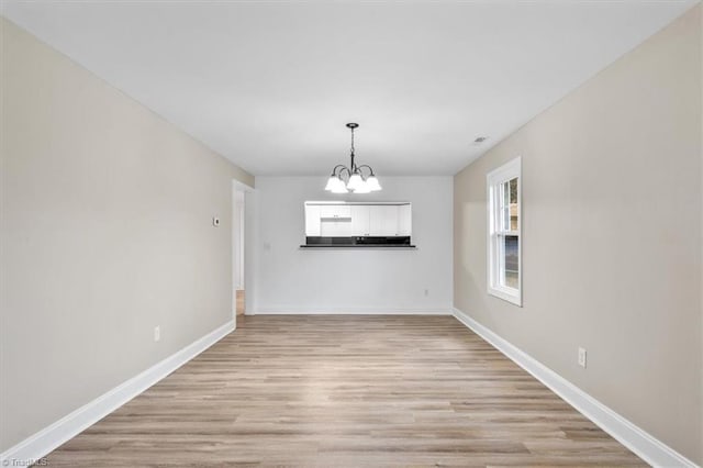 unfurnished dining area featuring a chandelier and light hardwood / wood-style floors