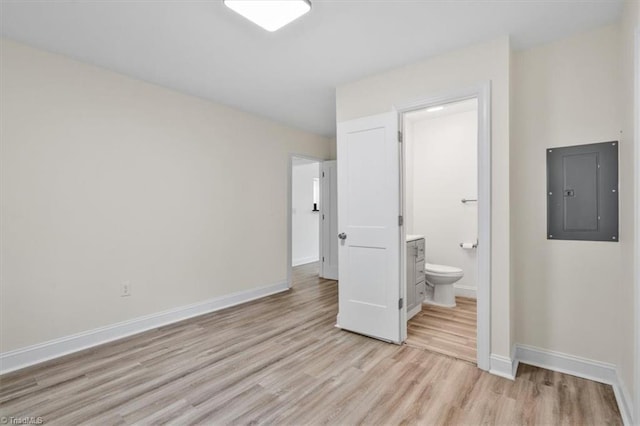 unfurnished bedroom with electric panel, light hardwood / wood-style flooring, and ensuite bathroom