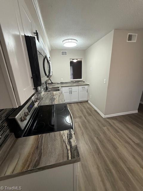 kitchen featuring visible vents, a textured ceiling, wood finished floors, white cabinetry, and appliances with stainless steel finishes