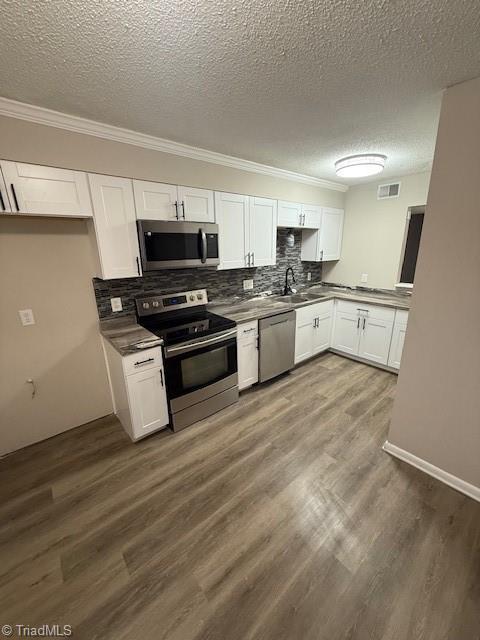 kitchen featuring visible vents, a sink, dark wood finished floors, appliances with stainless steel finishes, and white cabinets