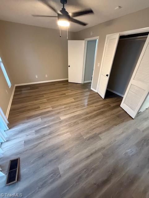 unfurnished bedroom with visible vents, ceiling fan, baseboards, and wood finished floors