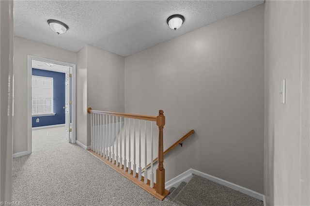 hallway with a textured ceiling and carpet floors