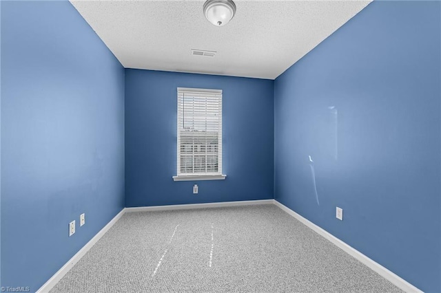 spare room featuring a textured ceiling and carpet floors