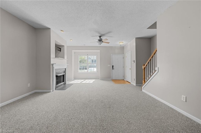 unfurnished living room featuring light carpet, ceiling fan, and a textured ceiling